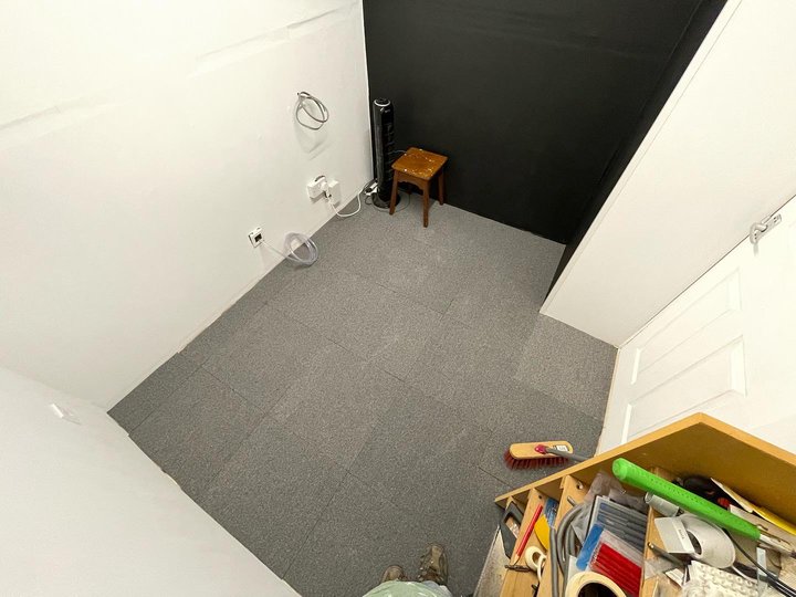 The walls have been papered and painted, the floor is covered with grey carpet tiles.