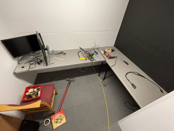 Worktops have been installed at sitting height and a computer setup of two monitors and a mac mini is ready to be installed. Various tools are also on the worktops.